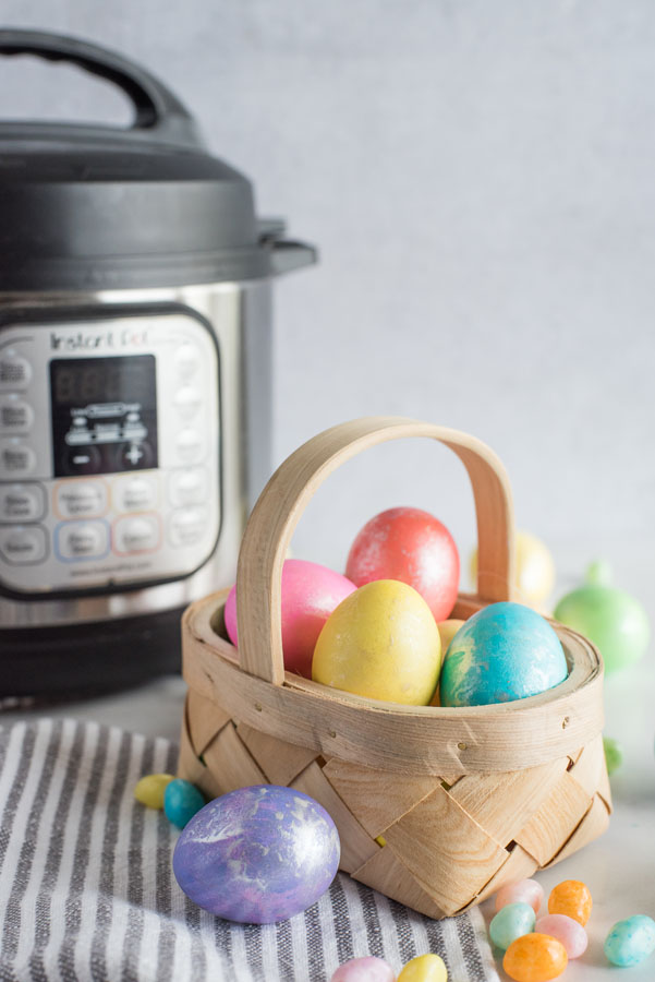 A basket of decorated Easter eggs placed in front of an Instant Pot.