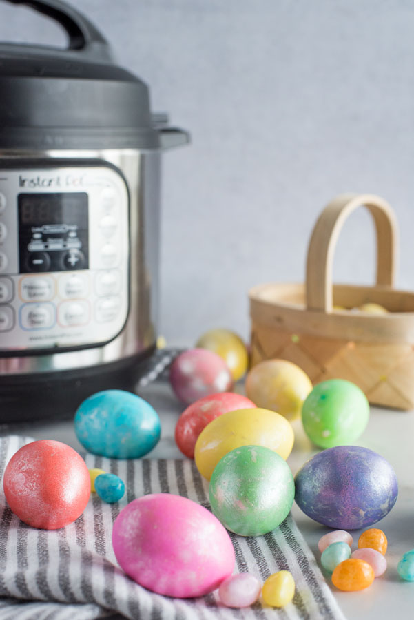 Easter eggs spread out on a table with jellybeans in front of an Instant Pot.