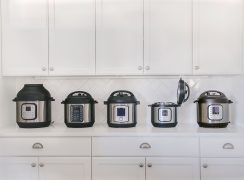 Five different models of Instant Pot on a white counter with white cabinets and a white tile backsplash in the background