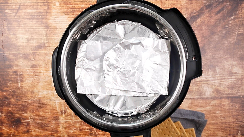 Instant Pot Vanilla Cheesecake with a Sour Cream Topping, going into the Instant Pot covered in foil for the second cook time