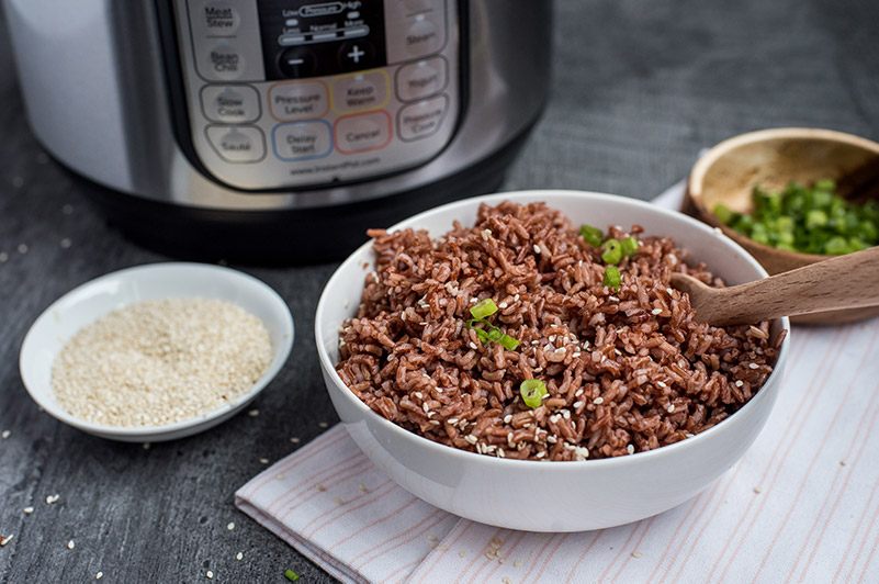 Pressure Cooker Pink Rice prepared with sesame seeds, chopped green onions, and an Instant Pot in the background