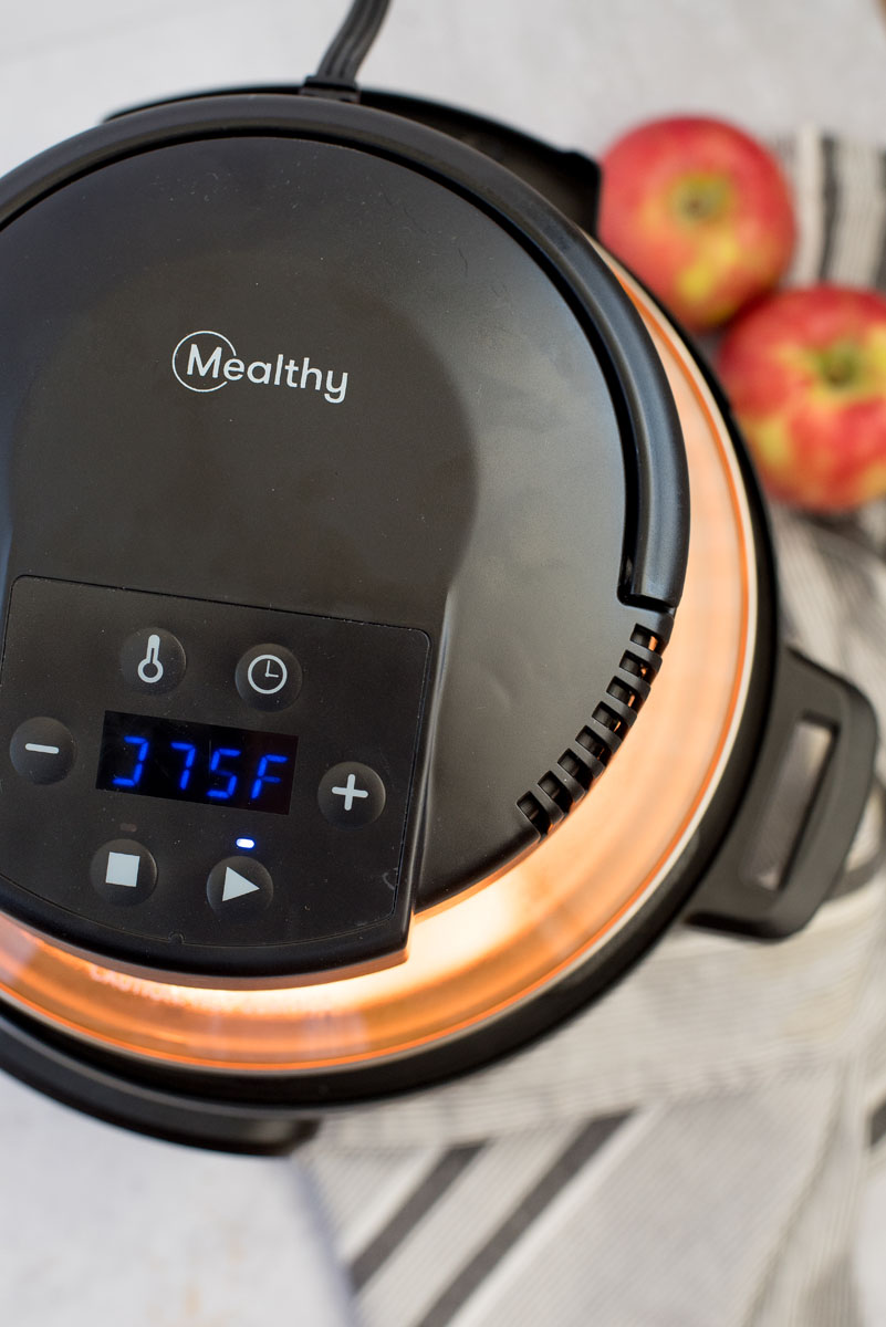 an overhead shot of the Mealthy CrispLid air fryer lid on and running, with apples in the background
