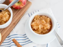 instant pot apple sauce in a small white dish with a wooden board behind