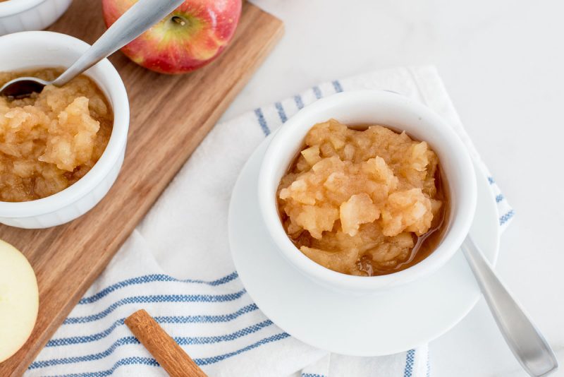 instant pot apple sauce in a small white dish with a wooden board behind