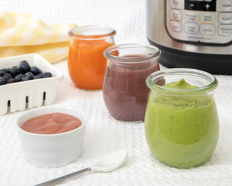 Different colors of Instant Pot baby food puree with an Instant Pot and fresh fruit in the background