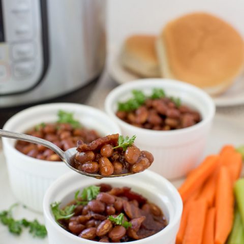 Instant pot baked beans in white ramekins with a spoonful being taken ou