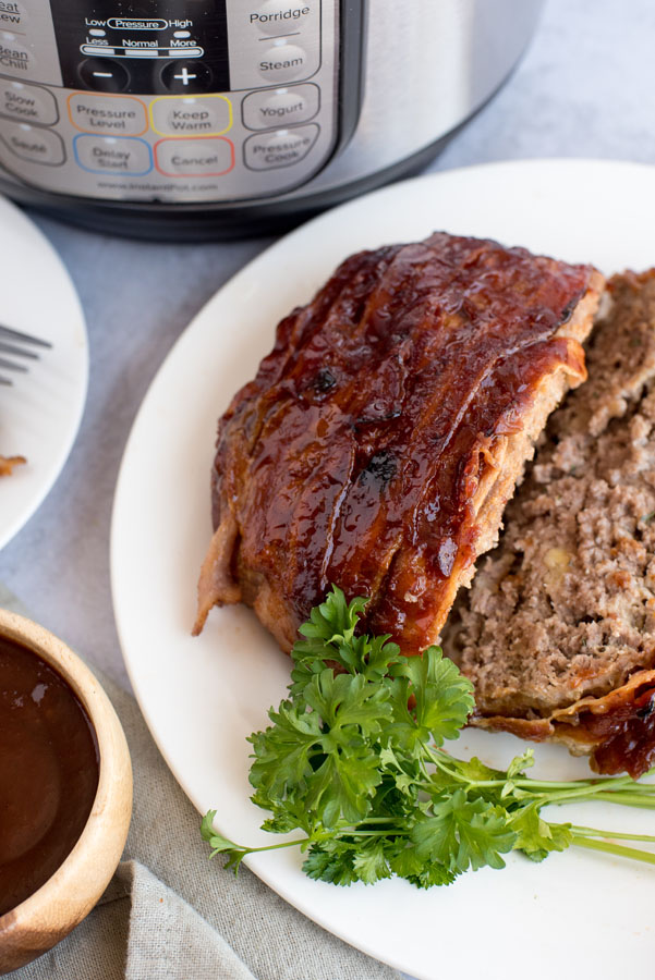 Pressure cooker meatloaf sliced and plated in front of an Instant Pot.