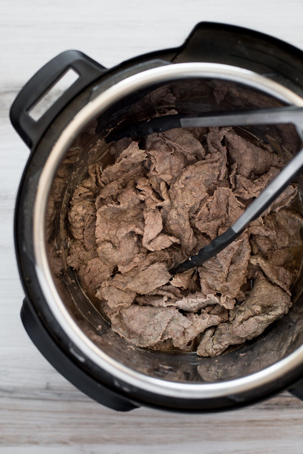 Overhead of pressure cooked thin sliced beef in an Instant Pot