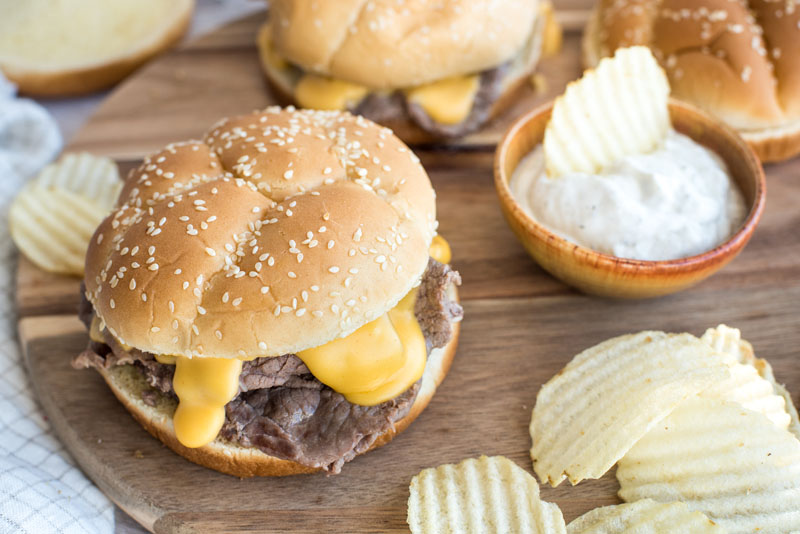 close up on instant pot shredded beef and cheddar sandwiches with potato chips and sour cream dipping sauce