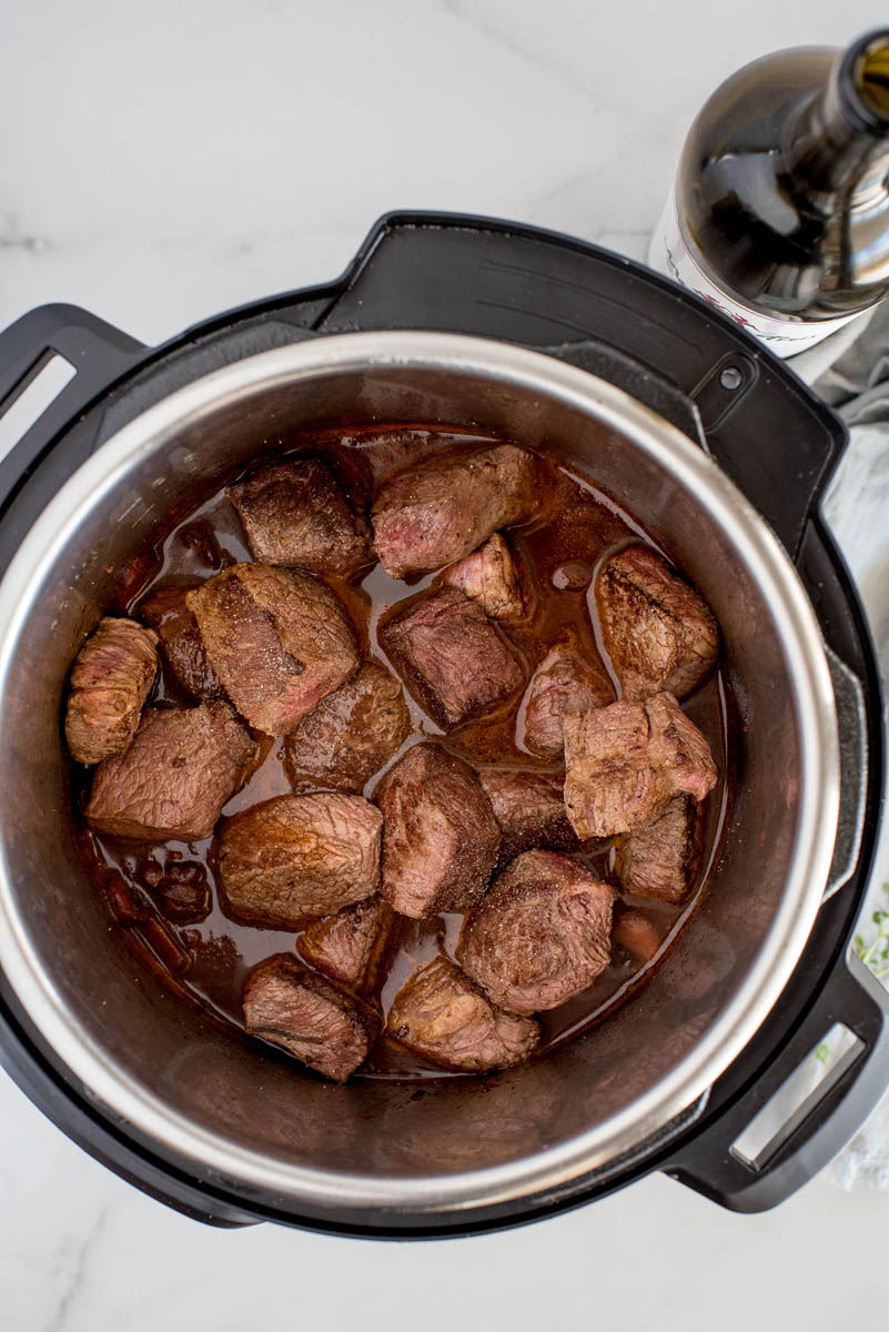 The browned beef and cooking liquid in the Instant Pot ready to be cooked fork tender.