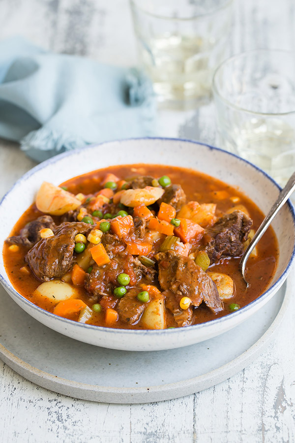 A bowl of Pressure Cooker Beef Stew served in a bowl with a light blue napkin on the table.