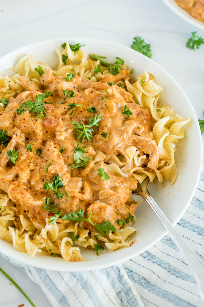 Close up of paprika chicken made in an Instant Pot and served over egg noodles with fresh parsley on top.