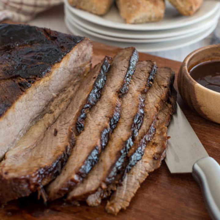 Pressure cooker brisket sliced with a bowl of bbq sauce.