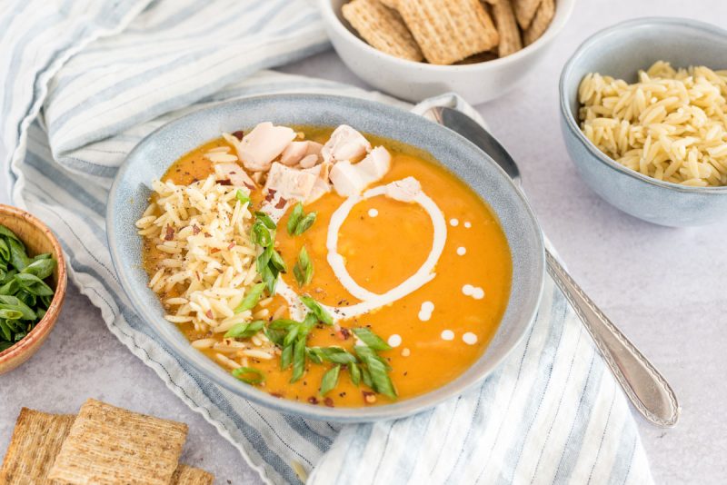 45 degree shot of Instant Pot Butternut Squash Soup with Chicken and Orzo, showing the orzo, chicken, and green onions before they're mixed in