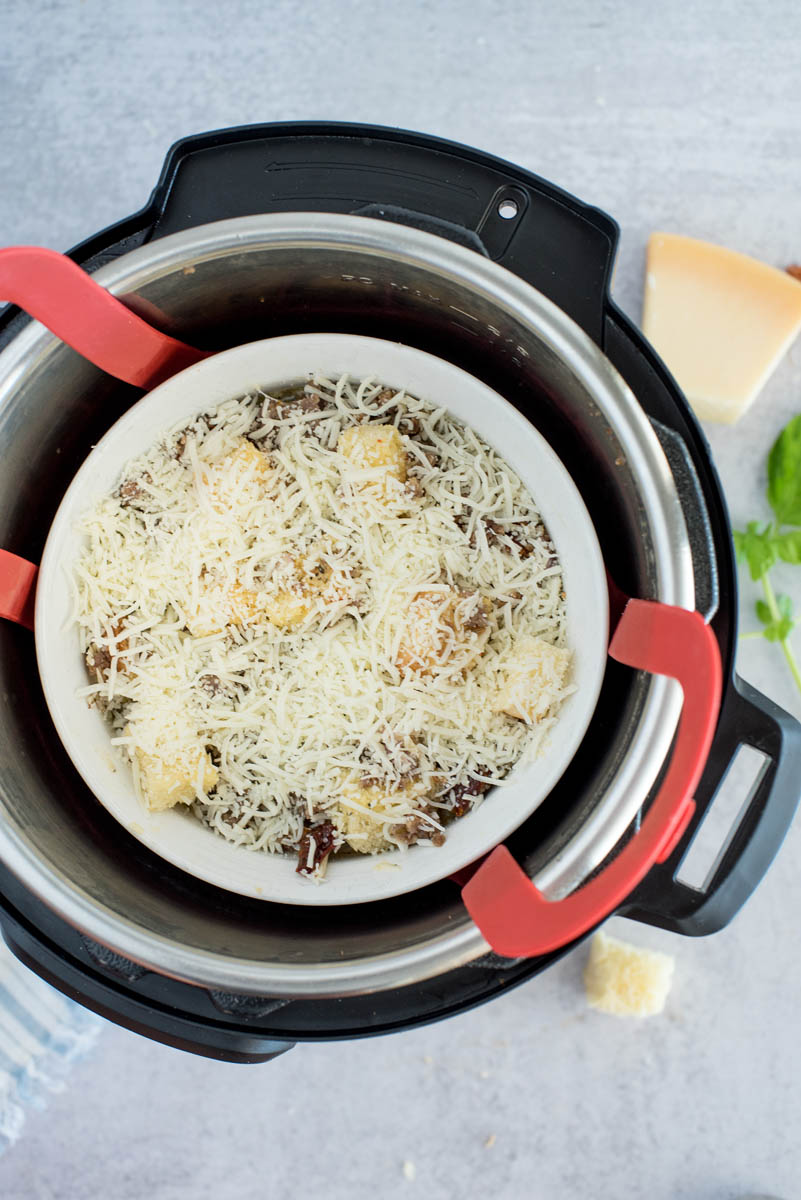 overhead of an instant pot with an uncooked casserole with cheese on top