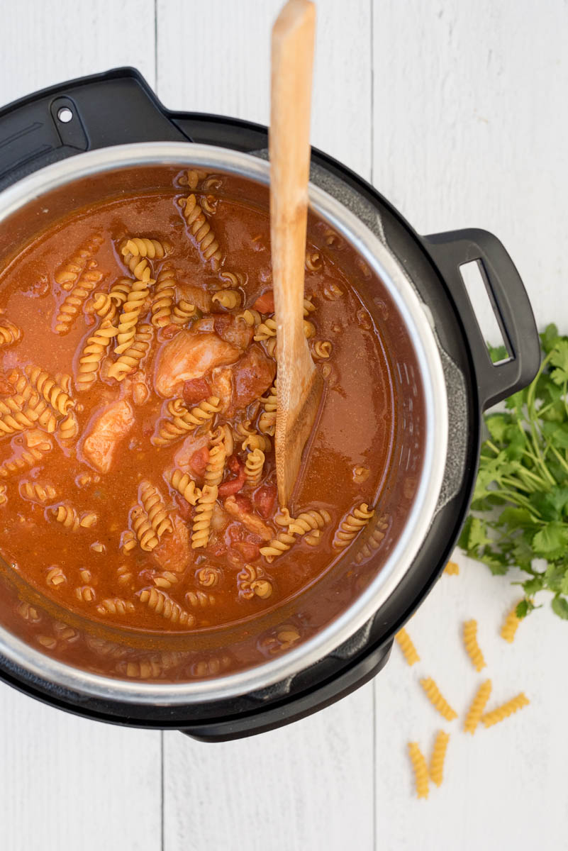 Overhead picture of ingredients added to an instant Pot for chicken enchilada pasta.