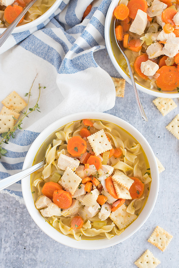 Pressure cooker chicken noodle soup served in a bowl and topped with crackers.