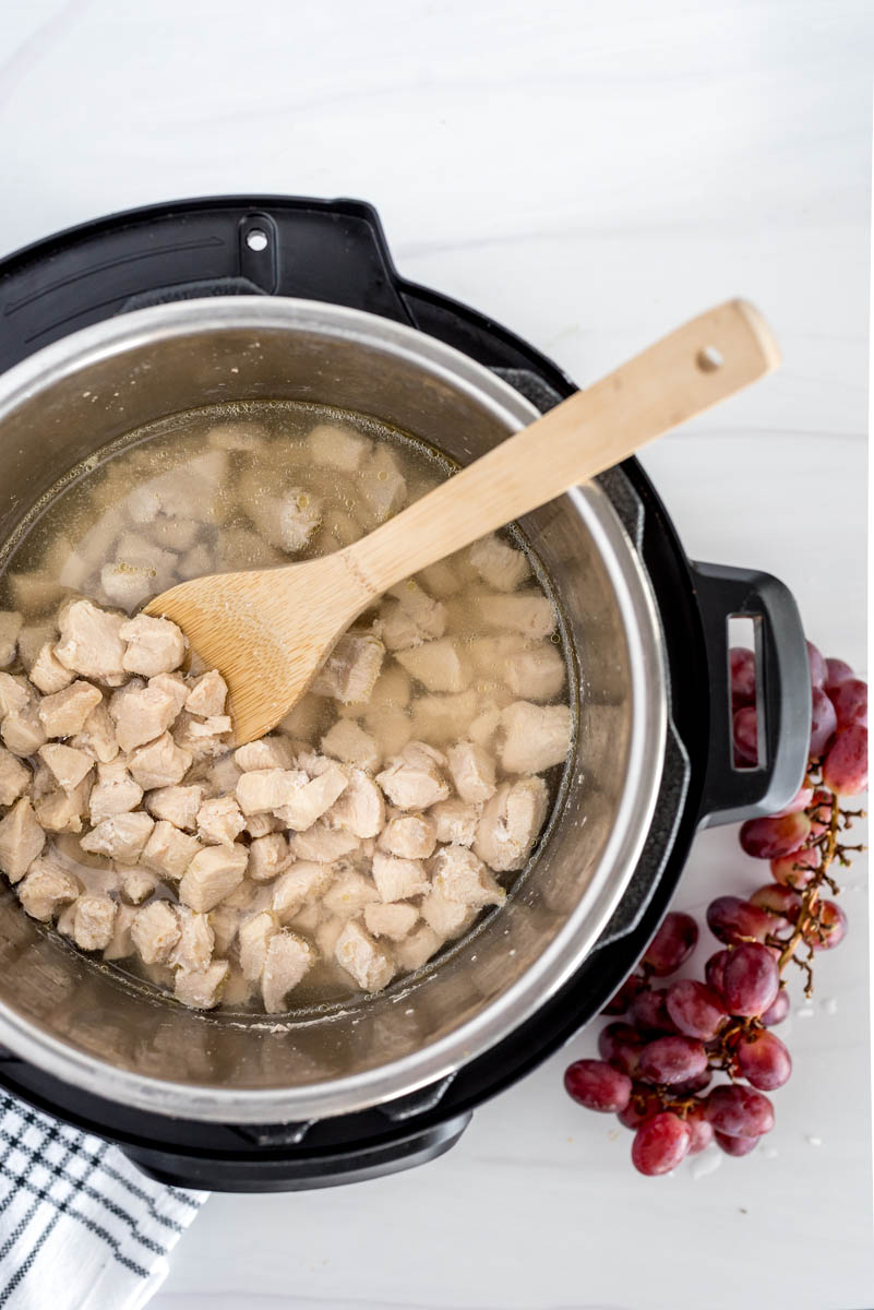 overhead of an instant pot with diced chicken breast cooking inside