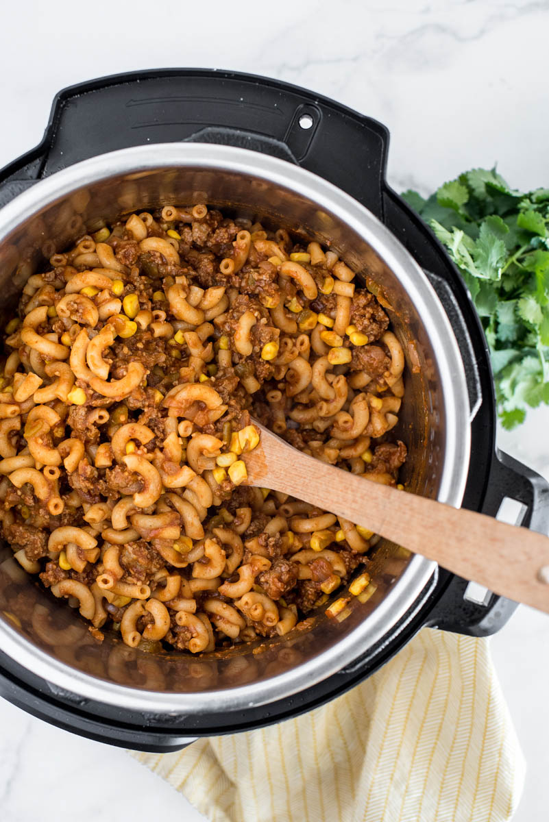 An overhead shot looking into an Instant Pot after the pasta has started cooking, with sausage visible