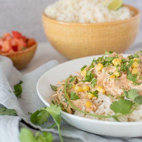 Close up of Instant Pot creamy chipotle chicken served over white rice and garnished with fresh cilantro and served in a white bowl.