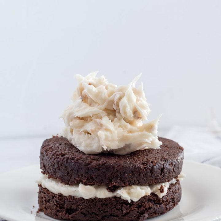 frosting a two layer chocolate cake on a white plate