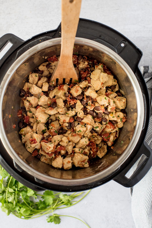 cooking diced chicken breast in an Instant pot with a wooden spoon for taco salad