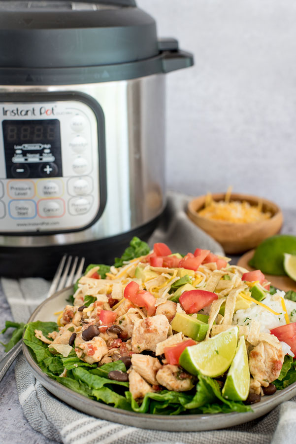 chicken taco salad with rice, dressing and chicken bites in front of an instant pot pressure cooker