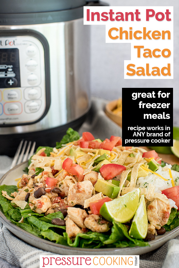 Pinterest image promoting pressure cooker chicken taco salad with text overlaid on a 45 degree shot of the salad, drizzled with dressing, cheese, dicied tomatoes, lime wedges on a bed of lettuce, with an Instant Pot in the background via @PressureCook2da