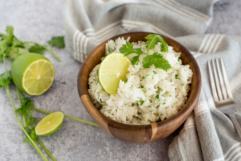 Instant pot cilantro lime white rice in a wooden bowl topped with fresh lime and cilantro