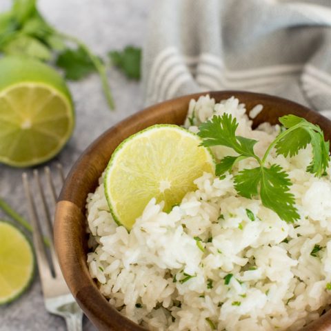 Instant pot cilantro lime white rice in a wooden bowl topped with fresh lime and cilantro