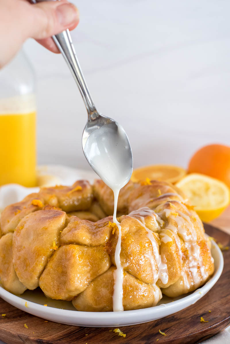 pouring citrus glaze over instant pot monkey bread