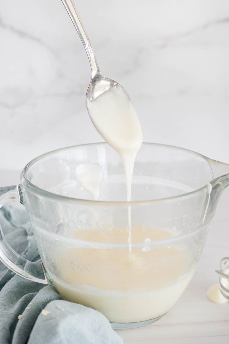 a mixing bowl filled with creamy white coconut icing for the bundt cake