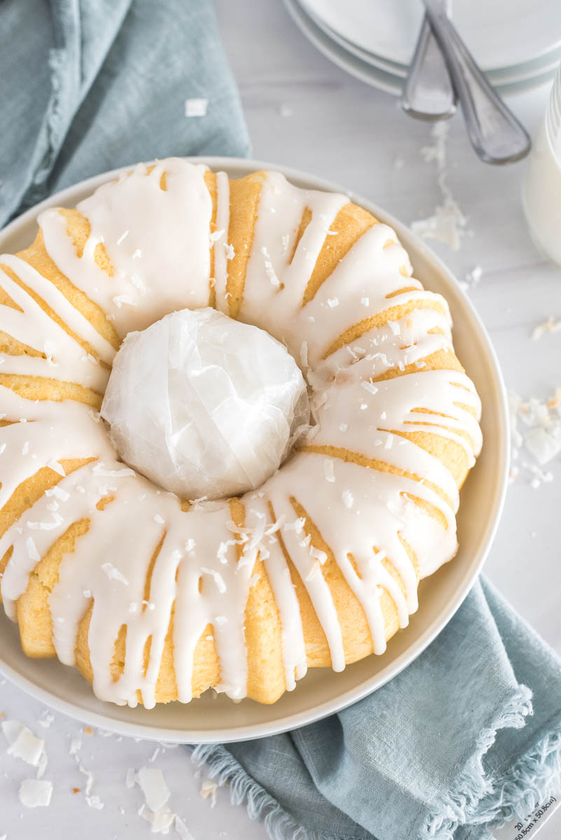 a ball of waxed paper in place for the coconut bundt cake, to help construct the bird nest decoration, with a blue napkin and white plates visible in the background