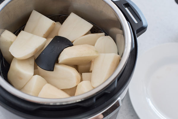 Step 2 of Instant Pot Mashed Potatoes: Diced potatoes inside the Instant Pot cooking pot, sitting on top of the steamer basket