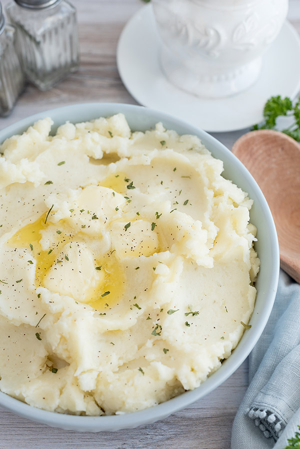 A serving bowl of Pressure Cooker Mashed Potatoes with salt and pepper in the background