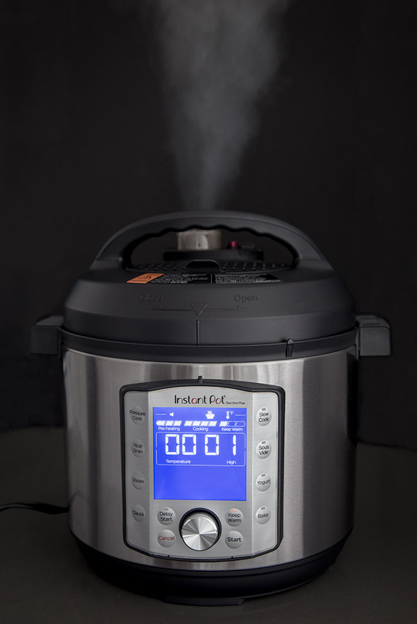 Instant Pot Evo Duo Plus quick release showing with a jet of steam coming out against a black background