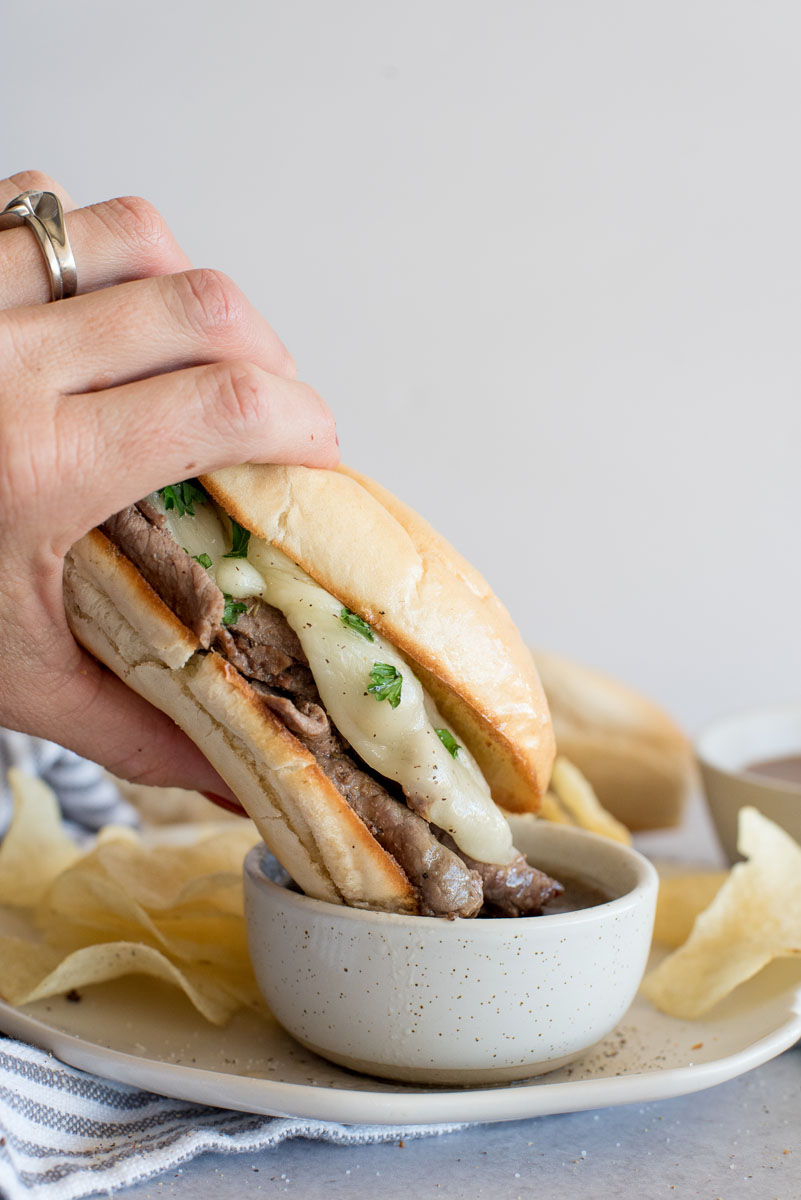 Dipping a pressure cooker French dip sandwich into au jus.