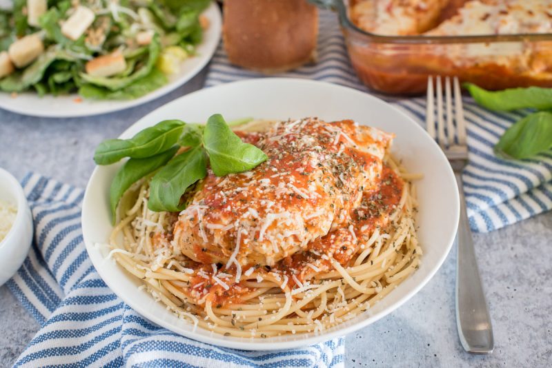 Close up shot of Instant Pot chicken marinara served over spaghetti and garnished with basil.