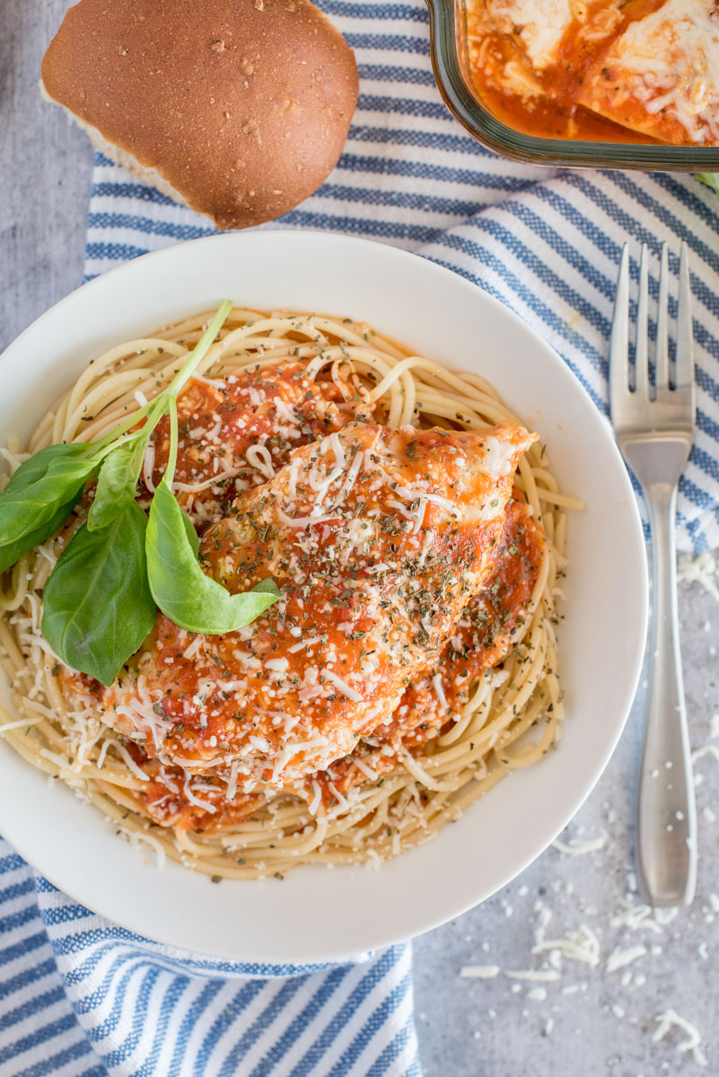 Overhead shot of chicken marinara that was cooked in a pressure cooker, that is served over spaghetti and garnished with fresh basil.