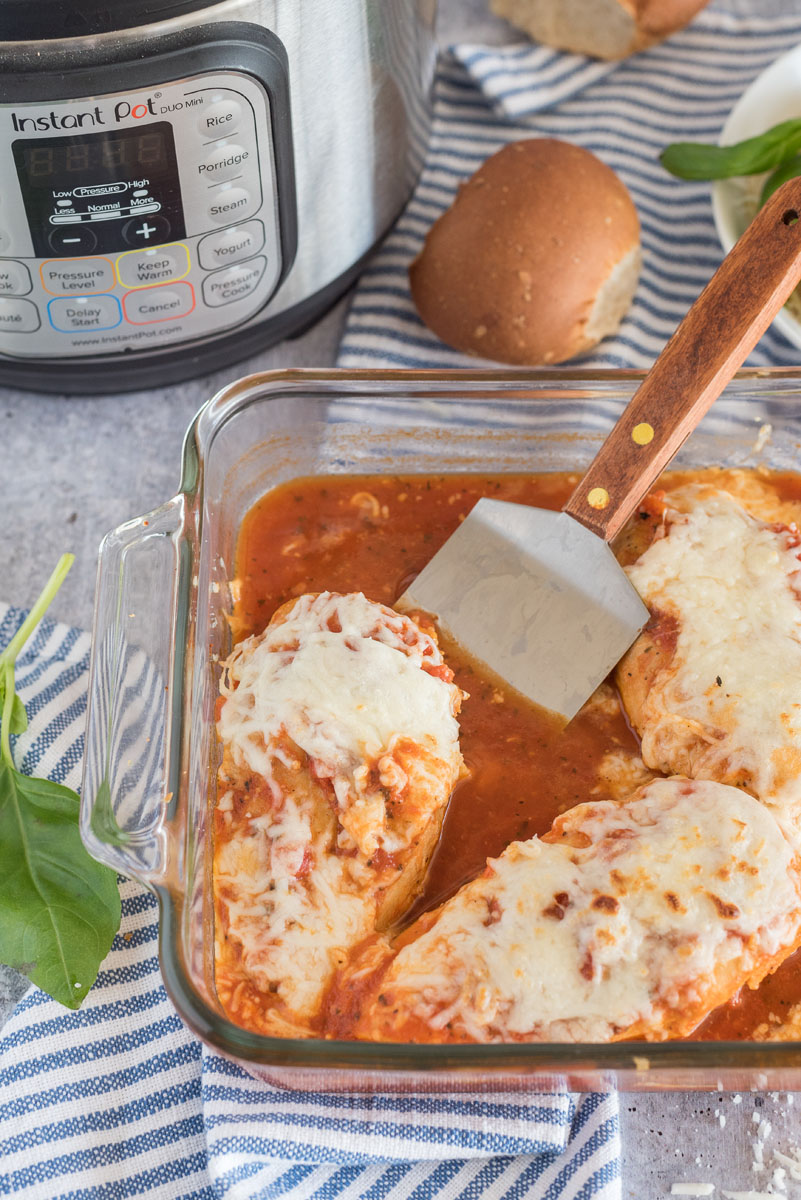 I Pyrex pan with chicken mozzarella and marinara sauce, with fresh basil and an Instant Pot in the background.