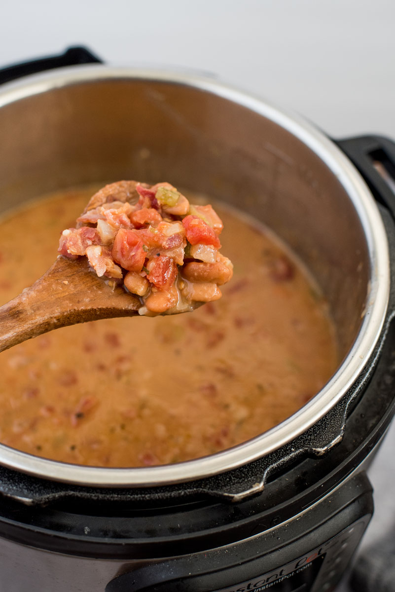 45 degree shot of beans, toomatoes, and bacon on a wooden spoon, ready to serve