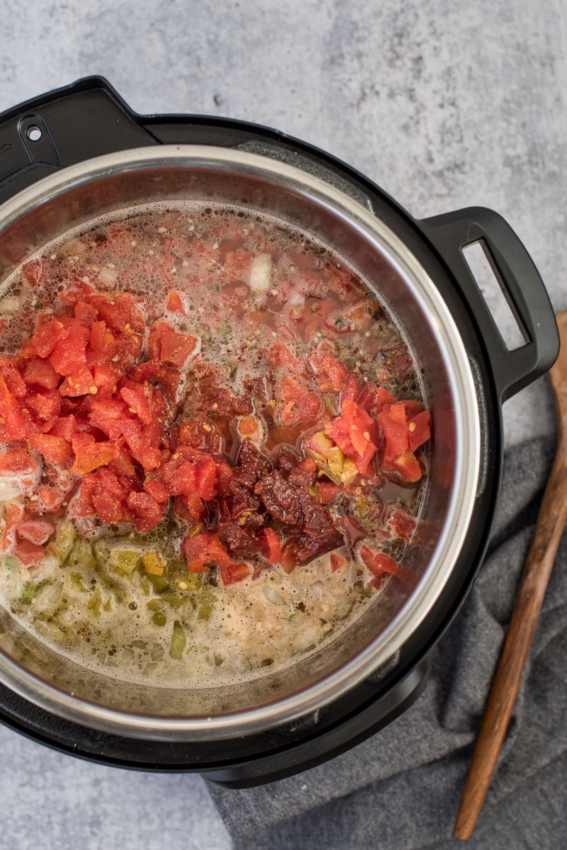 overhead shot inside an Instant Pot filled with beans, beer, broth, bacon, tomatoes, and chiles