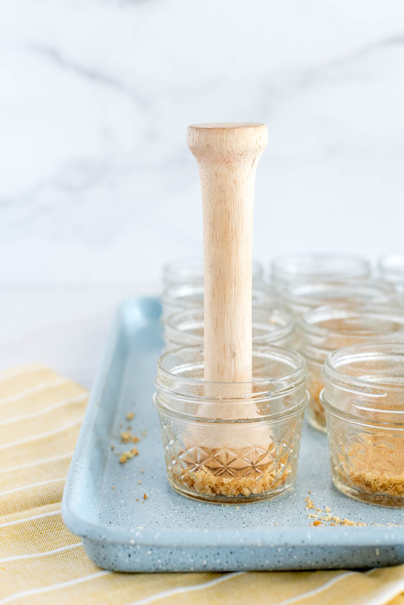 Using a tart tamper to push down on the cookie crumbs to make a nice crust.