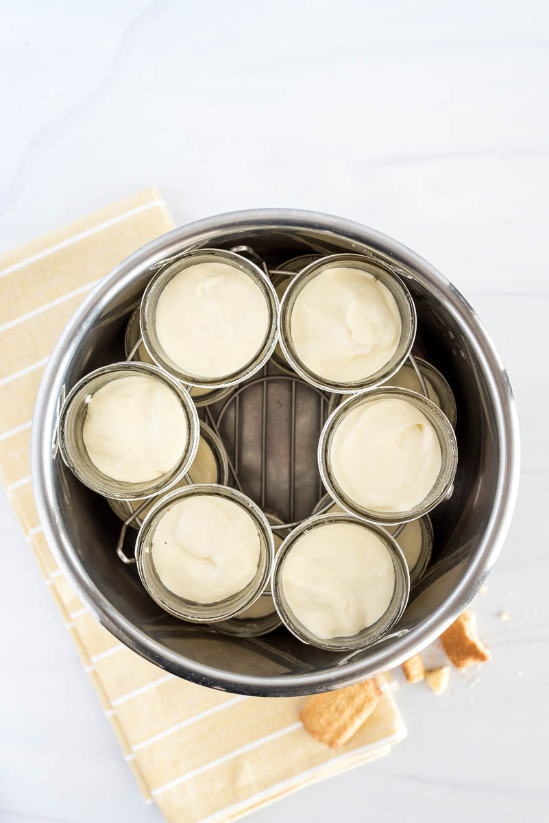 An overhead shot looking into an Instant Pot pressure cooker, filled with two sets of six filled mini mason jars stacked on top of each other