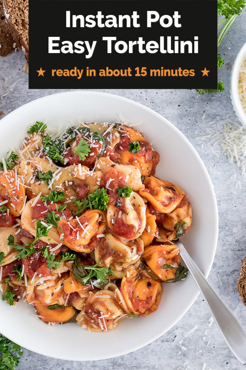 Overhead picture of easy Instant Pot Tortellini in a tomato basil sauce topped with parsley and parmesan cheese in a white bowl with a spoon.