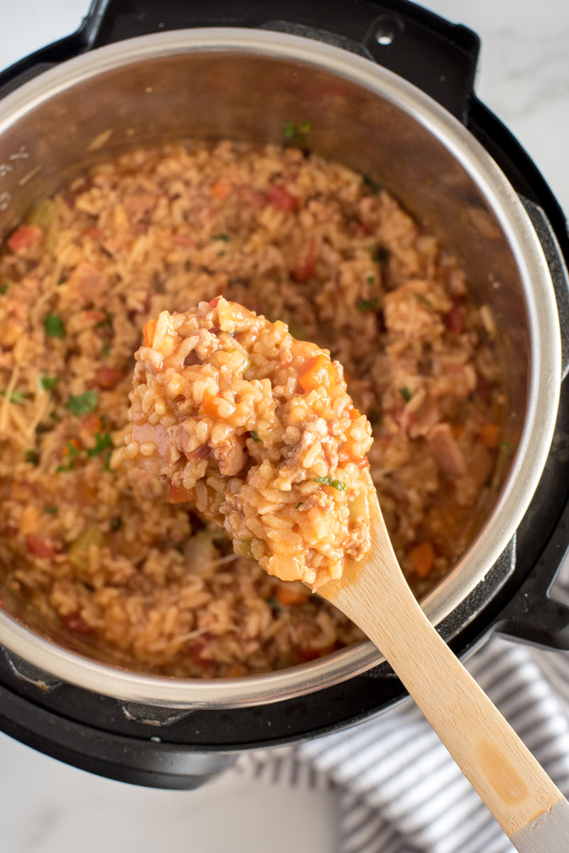 Overhead shot of Risotto Bolognese cooked in an Instant Pot and being served with a wooden spoon.