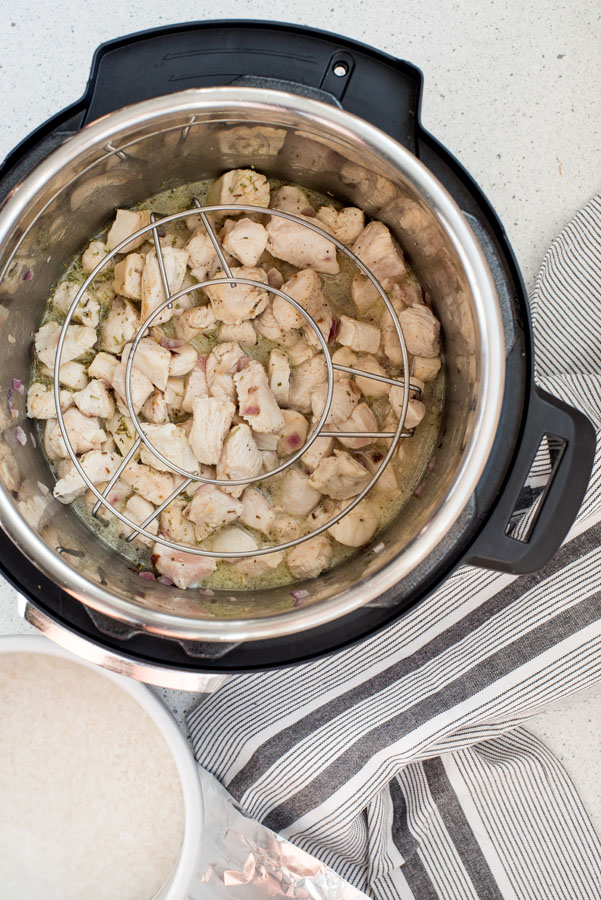 Preparing rosemary cashew chicken in an Instant Pot with a trivet placed over the chicken for pot in pot cooking.