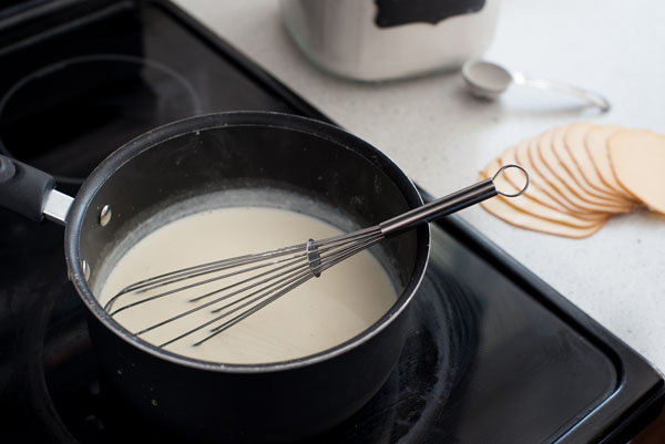 Preparing the Gouda cream sauce with a whisk on the stovetop  in a pan
