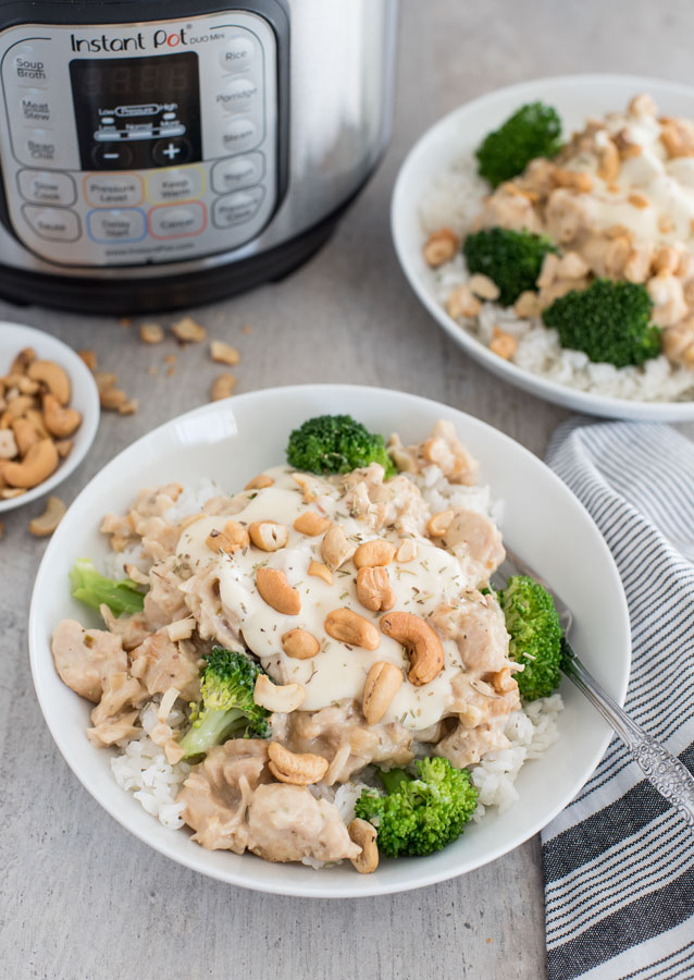 Overhead shot of a rosemary cashew chicken in a bowl with rice, cashews, and broccoli. Set in front of an Instant Pot.