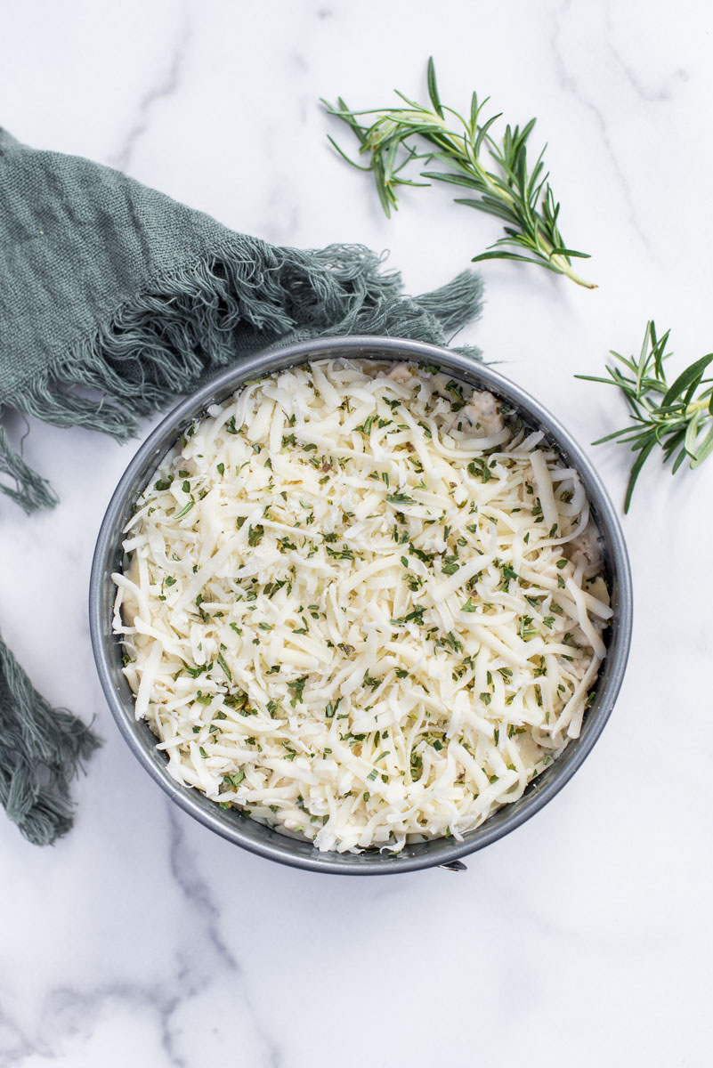 assembled rosemary white chicken lasagna in a springform cake pan before melting the cheese on top